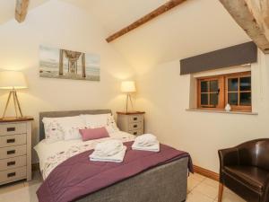 a bedroom with a bed with a chair and a window at The Cattle Byre in Corsham