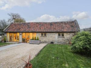 una casa de piedra con techo rojo y patio en The Cattle Byre, en Corsham