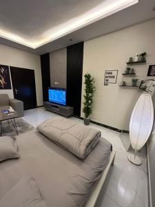 شقة أنيقة في العليا في الرياض: غرفة معيشة مع أريكة وتلفزيون