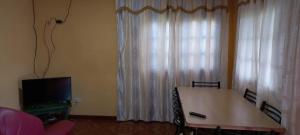 a living room with a table and a television and curtains at El Amanecer Don Zenon Lago Urugua-i in Puerto Libertad