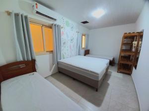 um pequeno quarto com 2 camas e uma janela em Casa para temporada c/ ar condicionado, próximo da praia e do Beco das Garrafas em Prado