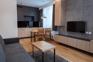 a kitchen and living room with a table and a tv at Aparthotel Zlatni Javor in Jahorina
