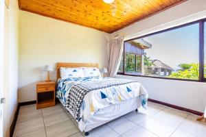 ein Schlafzimmer mit einem Bett und einem großen Fenster in der Unterkunft Hilltop Hideaway in Umdloti