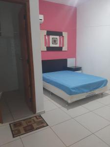 a small bed in a room with a pink wall at Flat Amarração 130 in Luis Correia
