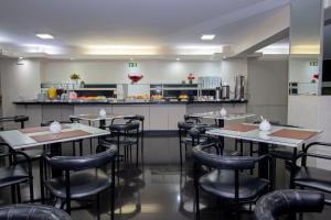 a restaurant with tables and chairs and a kitchen at Hotel Nacional Inn Curitiba Torres in Curitiba