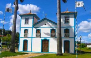 uma igreja azul e branca com duas palmeiras em Quinta Santa Bárbara em Pirenópolis