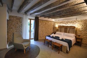 a bedroom with a bed and a chair at Calvario Plaza Hotel in Pollença