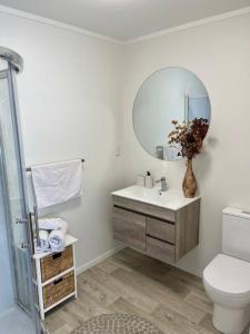 a bathroom with a sink and a toilet and a mirror at Pāpāmoa Beach Studio Oasis in Papamoa