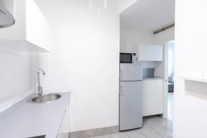 een witte keuken met een wastafel en een koelkast bij Nordic apartment Sagrada Familia in Barcelona