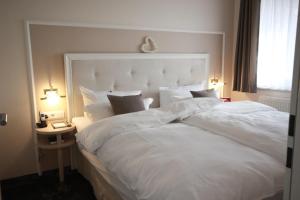 a large white bed in a room with a window at Suiten-Hotel mare Langeoog in Langeoog