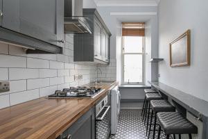 a kitchen with a stove and a counter with stools at Finnieston Apartment in Glasgow