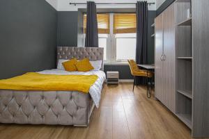 sypialnia z łóżkiem z żółtą pościelą i biurkiem w obiekcie Finnieston Apartment w Glasgow
