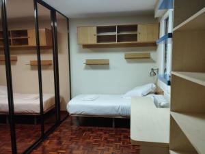 Habitación pequeña con 2 camas y estanterías en Alojamientos Mendebaldea, en Pamplona