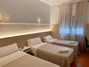 a hotel room with three beds and a window at Can Setmanes by CozyCatalonia in Blanes