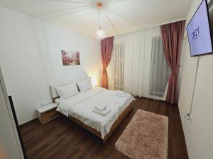 ein kleines Schlafzimmer mit einem weißen Bett und einem Teppich in der Unterkunft Urban Luxury Flats - Cozy Apartments at Coresi Mall #Brasov in Braşov