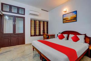 1 dormitorio con 1 cama grande con almohadas rojas en OYO Flagship 81056 Poptavern Heritage en Kovalam