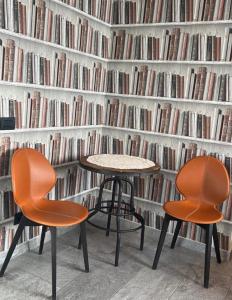two chairs and a table in front of a wall of books at Agriturismo da Mamma in Alba