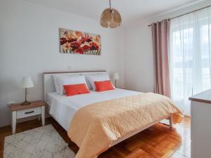 a white bedroom with a bed with two red pillows at Sea-view Apartments Klara - Viganj in Viganj