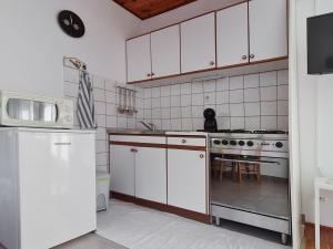 cocina con armarios blancos, fogones y nevera en Sea-view Apartments Klara - Viganj, en Viganj