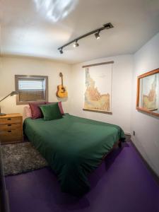 - une chambre avec un lit vert et une guitare sur le mur dans l'établissement Mountain Majesty - Newly Remodeled, à Driggs