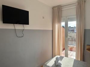 1 dormitorio con TV de pantalla plana en la pared en Can Setmanes by CozyCatalonia, en Blanes