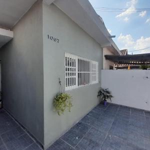 um edifício branco com um portão e plantas nele em Casa Bela na Praia Grande