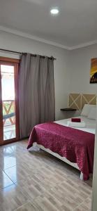 um quarto com uma cama com um cobertor roxo em Pousada e Restaurante Paraíso Natural em Jijoca de Jericoacoara
