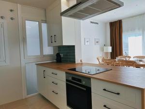 a kitchen with white cabinets and a black stove top oven at Apartament a Palamós amb plaça de parking in Palamós