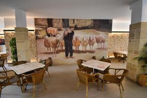 a man standing in front of a painting in a restaurant at Calvario Plaza Hotel in Pollença