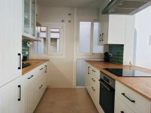 a kitchen with white cabinets and black appliances at Apartament a Palamós amb plaça de parking in Palamós