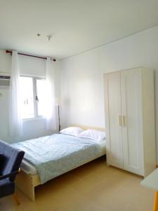 a white bedroom with a bed and a window at Ace That Condo Staycation Cheer Residences beside SM Marilao in Marilao