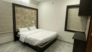 a bedroom with a bed with white sheets and a window at Ahasa Bacardi in Hyderabad