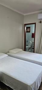 una camera con 2 letti e un bagno con specchio di Pousada e Restaurante Paraíso Natural a Jijoca de Jericoacoara