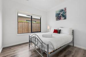 - une chambre blanche avec un lit et une fenêtre dans l'établissement Nirvana Armstrong Creek Family Beach Home, à Mount Duneed