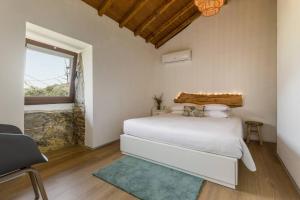 sypialnia z białym łóżkiem i oknem w obiekcie Casas de Xisto w mieście Raiva