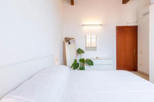a bedroom with a white bed and a wooden door at Penthouse with Terrace in historic centre in Cagliari