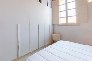 Cette chambre blanche dispose d'un lit et d'une fenêtre. dans l'établissement Penthouse with Terrace in historic centre, à Cagliari