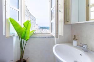 a bathroom with a sink and a window and a plant at Penthouse with Terrace in historic centre in Cagliari