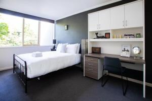 - une chambre avec un lit et un bureau avec un ordinateur dans l'établissement Leafy Toorak two bedroom executive apartment, à Melbourne