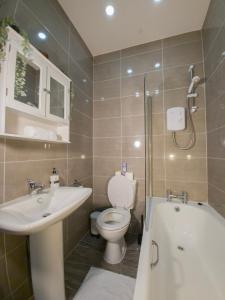 a bathroom with a toilet and a sink and a tub at Cosmeston Cwtch by Property Promise in Cardiff