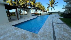 a swimming pool next to a house with palm trees at Oceanfront Cristamar Apartment in Cabarete