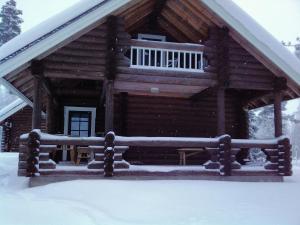 ブオカッティにあるVuokatti Cottagesの雪の中にポーチ付きのログキャビン