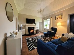 a living room with a blue couch and a fireplace at Killawalla Cottage, Westport. in Westport