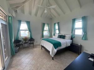 Schlafzimmer mit einem Bett mit grüner Bettwäsche und Fenstern in der Unterkunft Amazing mountain top home with stunning views in Marigot