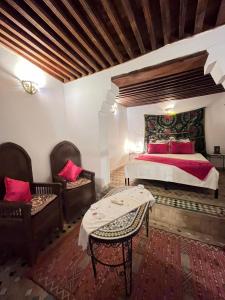 um quarto com uma cama, 2 cadeiras e uma mesa em Dar Labchara em Fez