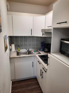 a small kitchen with white cabinets and a sink at Wolkenlos in Butjadingen
