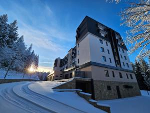a building in the snow on a snow covered road at Aparthotel Zlatni Javor in Jahorina