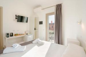 a white bedroom with a bed with towels on it at TS ROOMS - Guest House Deidda in San Sperate