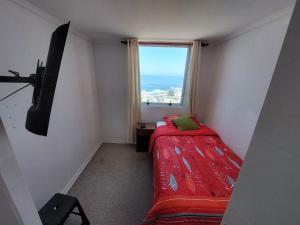 um pequeno quarto com uma cama e uma janela em LABBE Departamento Hermosa Vista al Mar em Iquique