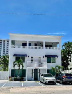 Ocean Breeze Free Parking Apt 2 في فورت لاودردال: بيت ابيض وسيارتين متوقفتين في موقف سيارات